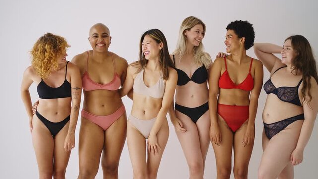 women in underwear are laughing and hugging each other, celebrating body positivity and female friendship against a white background