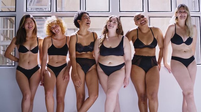 beautiful multi-ethnic models with different body types pose together in black underwear, showcasing diversity and body positivity on a clean white background