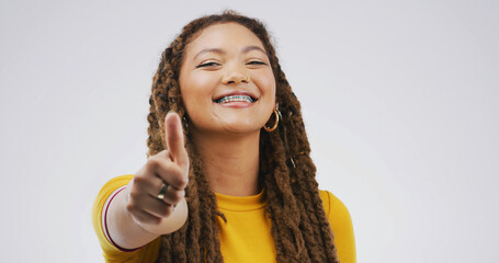 Black woman, braces and thumbs up in studio for approval feedback and emoji on white background....
