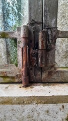 Close-up of a rusty hinge on an old metal gate, showing age and weathering.