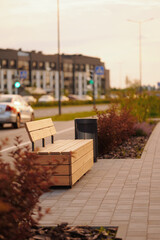 urban street bench near roadway in residential area during sunset. modern wooden seating blends...