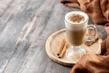 Maple Latte with Cinnamon in Glass Mug on wooden table. Copy space