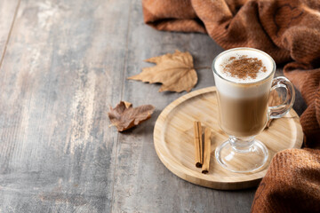 Maple Latte with Cinnamon in Glass Mug on wooden table. Copy space