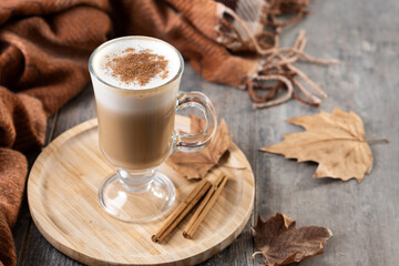 Maple Latte with Cinnamon in Glass Mug on wooden table. Copy space