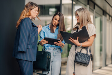 Businesswomen collaborating outdoors using digital tablet and documents