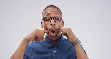 Portrait, funny face and black man in studio with goofy expression on white background. Silly,...