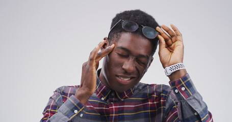 Black man, headache and glasses with stress in studio with mockup space, tired or vertigo on white...