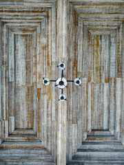 A symmetrical view of a weathered wooden ceiling with geometric patterns and a central light...