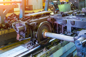 A locomotive bogie with a wheel pair on rails near a repair pit in a depot hangar