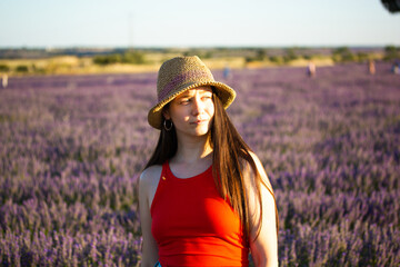 Young woman in a straw hat poses in a field of purple lavender during golden hour Serene girl...