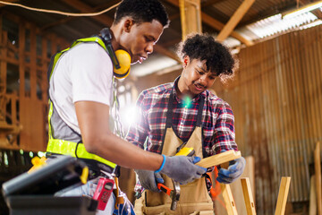 Two professional African carpenters are working together in sawmill or workshop.