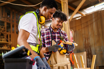 Two professional African carpenters are working together in sawmill or workshop.