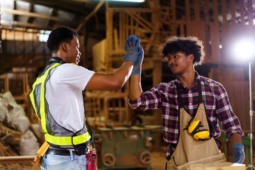 Two professional African carpenters are working together in sawmill or workshop.