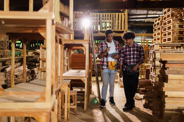 Two professional African carpenters are working together in sawmill or workshop.