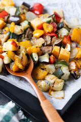 Roasted vegetables on a baking tray on black background