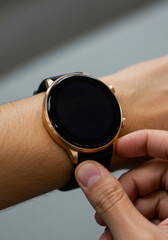 A hand adjusts a sleek, round-faced smartwatch with a golden frame and black strap