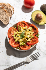 Top view of avocado and tomato salad on kitchen countertop background