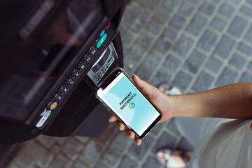 Woman paying for parking ticket using phone. Electronic payments. NFC technology. Fast mobile payments. Convenience and security