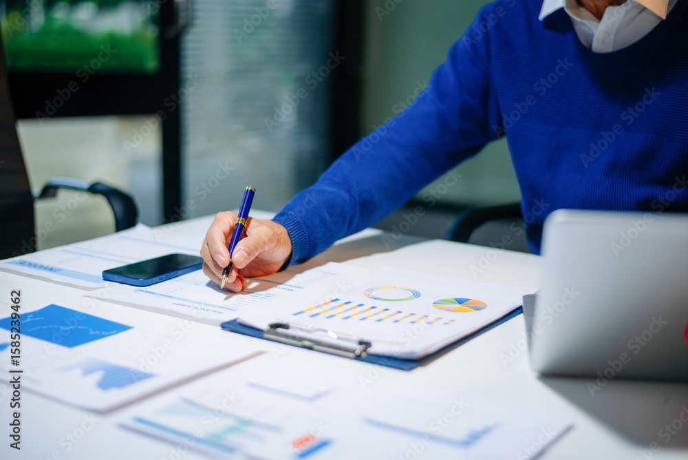 Poster bussinessman analyzing sales data and economic growth and pointing at business report document with 