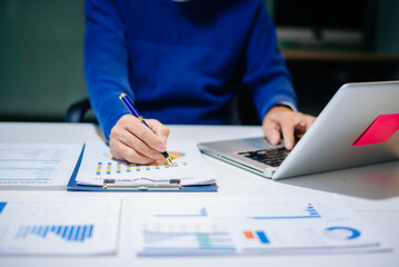 business documents on office desk with laptop and smart phone and graph business diagram and man working