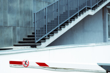 Obraz premium urban car parking street space renting place with red white barrier stick and gray wall stairway
