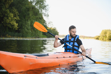 Kayaker paddling orange kayak on river in summer