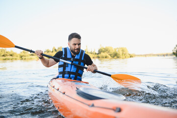 Kayaker paddling kayak on river in summer day