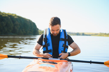 Kayaker wearing life vest and preparing for kayaking adventure on river