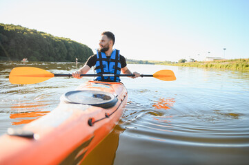 Kayaker paddling orange kayak on calm lake or river