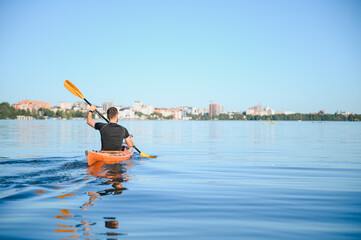 Kayaker paddling on calm lake with city skyline in background