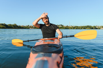 Tired kayaker wiping sweat from forehead while kayaking on lake in summer