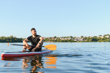 Sportsman relaxing on sup board paddling on lake in summer