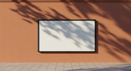 Blank horizontal black frame mockup on a sunlit terracotta wall outdoors, with realistic shadows from leaves creating a natural background for a poster or advertisement.