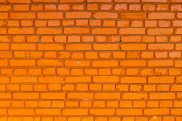 Obraz premium Textured brick wall painted in orange outdoors in bright daylight