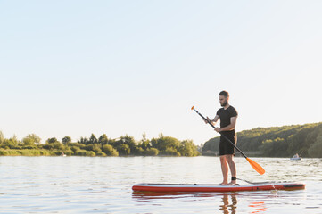 Sportsman paddling on sup board at sunset on the lake