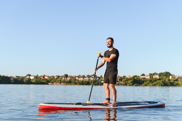 Sportsman paddling on sup board on lake in summer