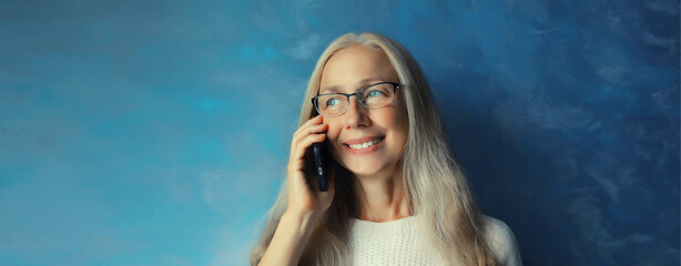 Portrait of happy smiling mature woman calling on mobile phone talking on smartphone at home