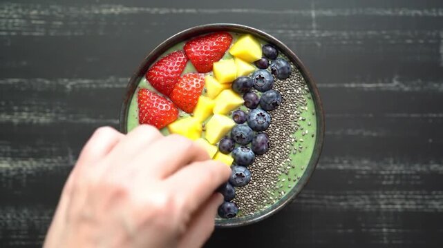 Colorful smoothie bowl arrangement: A vibrant smoothie bowl artfully arranged with fresh strawberries, mango cubes, blueberries, and chia seeds.