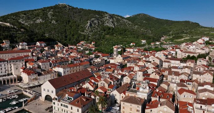 Aerial pull back shot of a town located in between hills at Hvar in Croatia. Nature landscape.