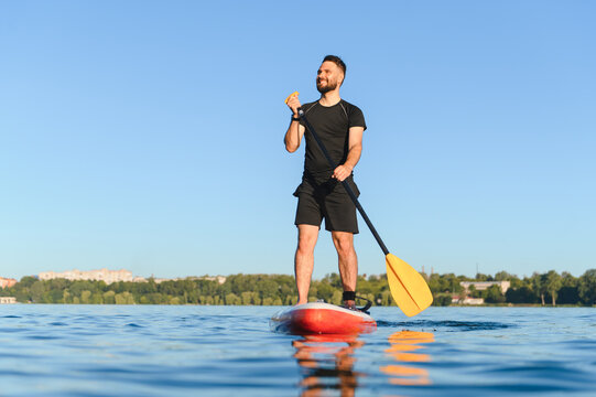 Sportsman paddling on sup board on lake enjoying paddle boarding - Powered by Adobe