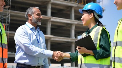 Two construction professionals shake hands at a bustling building site, while team members in safety gear observe. Collaboration and teamwork are key elements at this project