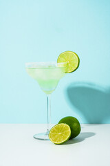 Margarita cocktail. Summer alcohol drink with silver tequila, liqueur, lime juice, sugar syrup, salt and ice on blue background.
