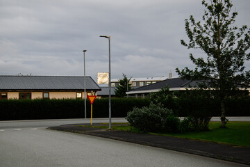 Quiet residential street in Akranes with trees, houses, and overcast skies