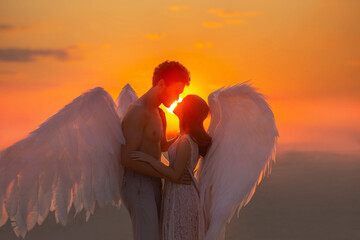 blurred dark silhouette two angles meet at sunset hug. Lovers muscular man and tender woman marry in heaven. concept love fidelity. warm color orange sky red sun light sun. Carnival costume wings