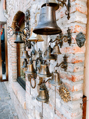 Historical brass bells displayed on a rustic stone wall in a quaint market street
