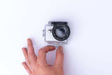 A person's hand holding a GoPro sports camera, isolated on white background. Top view.