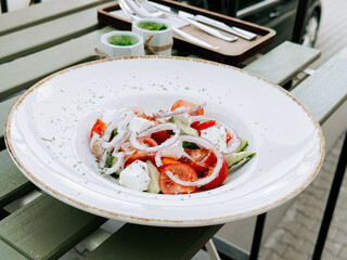 Fresh salad served outdoors on a green table during a sunny day