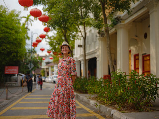 Young woman in ethnic dress and hat exploring the festive streets of George Town, Malaysia, during...