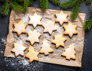 Freshly baked Christmas cookies shaped like stars and trees display beautifully on baking paper with festive decorations