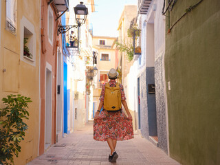 Woman in dress strolls through colorful streets of Spanish coastal town of La Vila Joiosa . sunny...